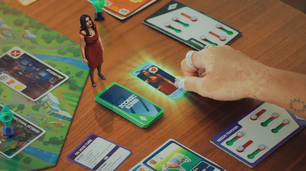 A close-up of Goliath Game's The Sims Board Game showing a hand grab a card while Bella Goth looks at them.
