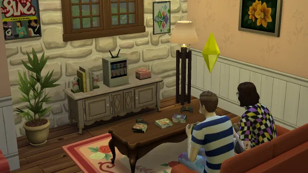 Two Sims playing a video game on a console surrounded by The Sims merchandising. It's a pink and white cottage.