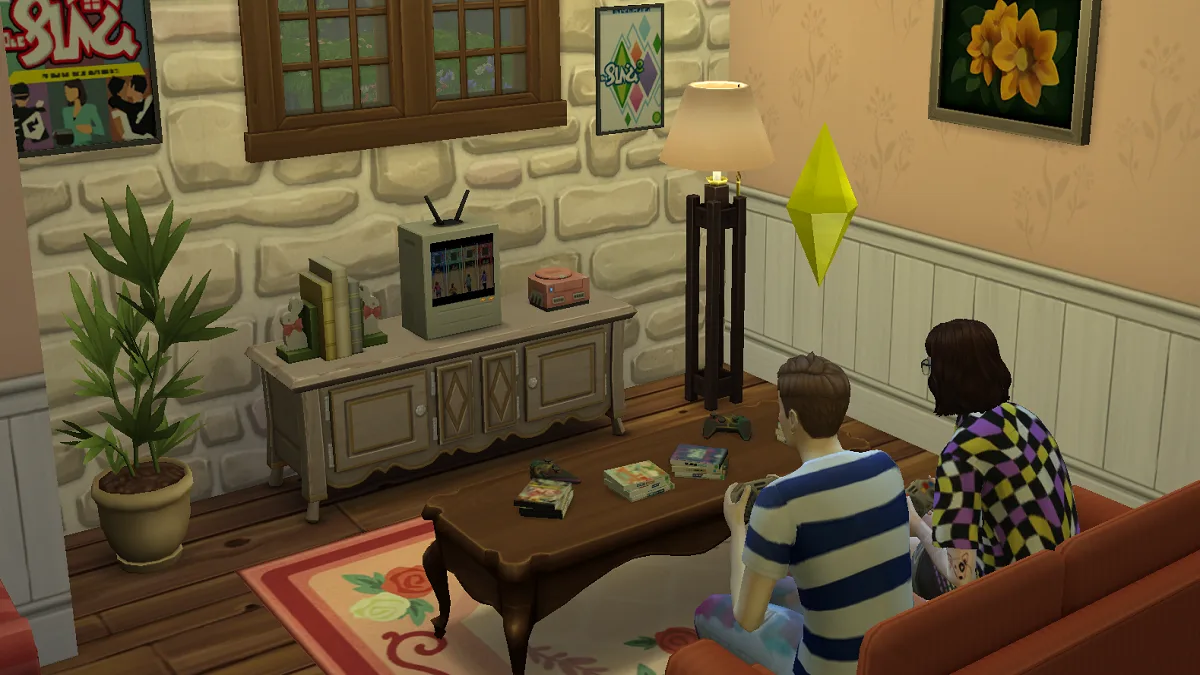 Two Sims playing a video game on a console surrounded by The Sims merchandising. It's a pink and white cottage.