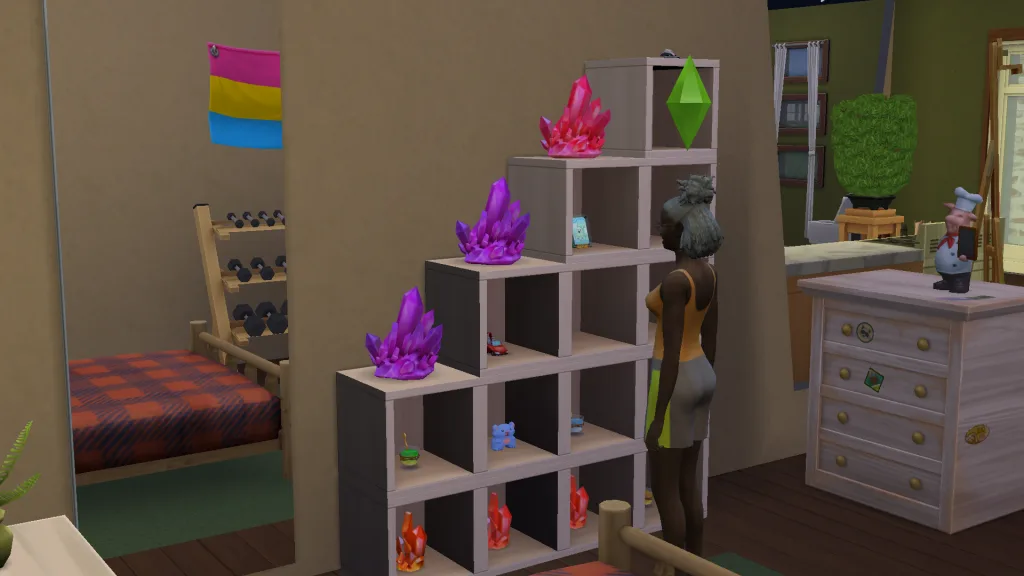 A Sim stood in front of some modular furniture in her cluttered bedroom showing crystals, toys, and potions, alongside some excise equipment, a mirror, bed, and a chest of drawers.