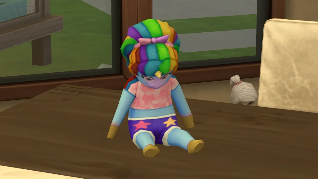 A sad looking pegicorn doll - A blue pegasus unicorn - wearing rainbow clothes in The Sims 4 Adventure Awaits.